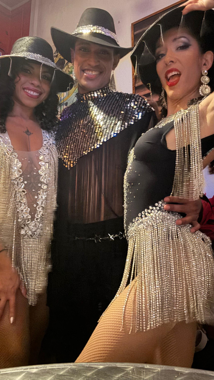 Deux danseuses et un danseurs avec leurs tenues noir et doré à franges et avec un borsalino