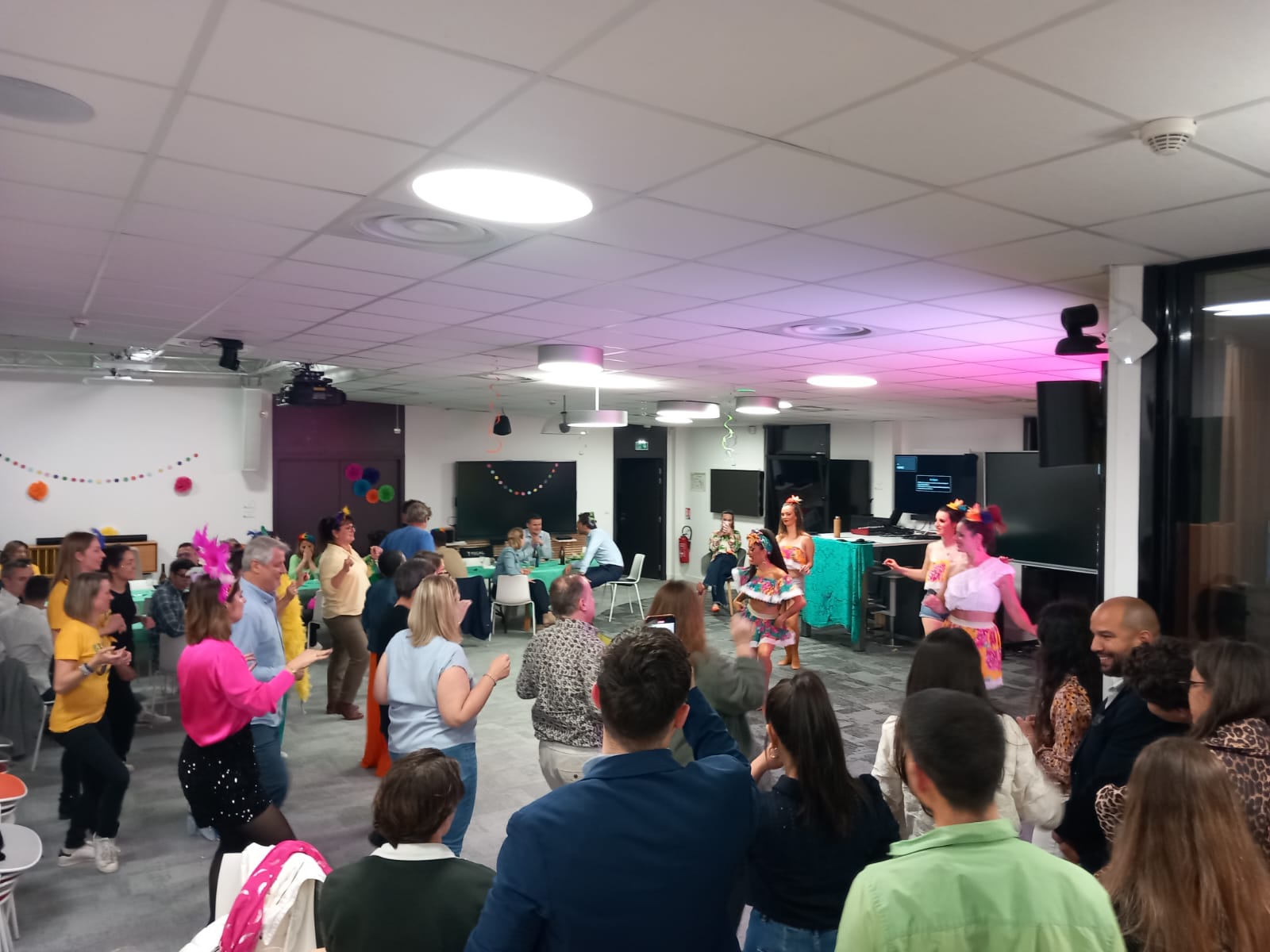 Les invités de dos s'essayent à danser tous ensemble avec les danseuses qui leur montrent