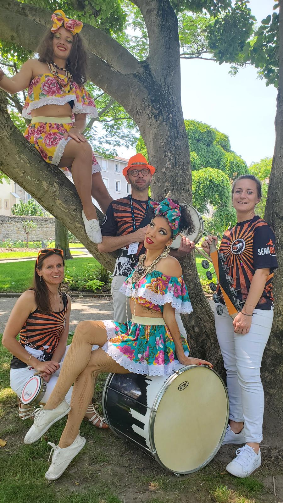 Le groupe de percussions Senario et deux danseuses de samba avec la tenue à fleurs et broderie anglaise